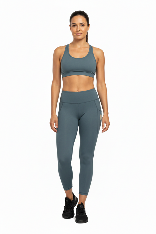 Woman wearing a gray sports bra and leggings set on a white background