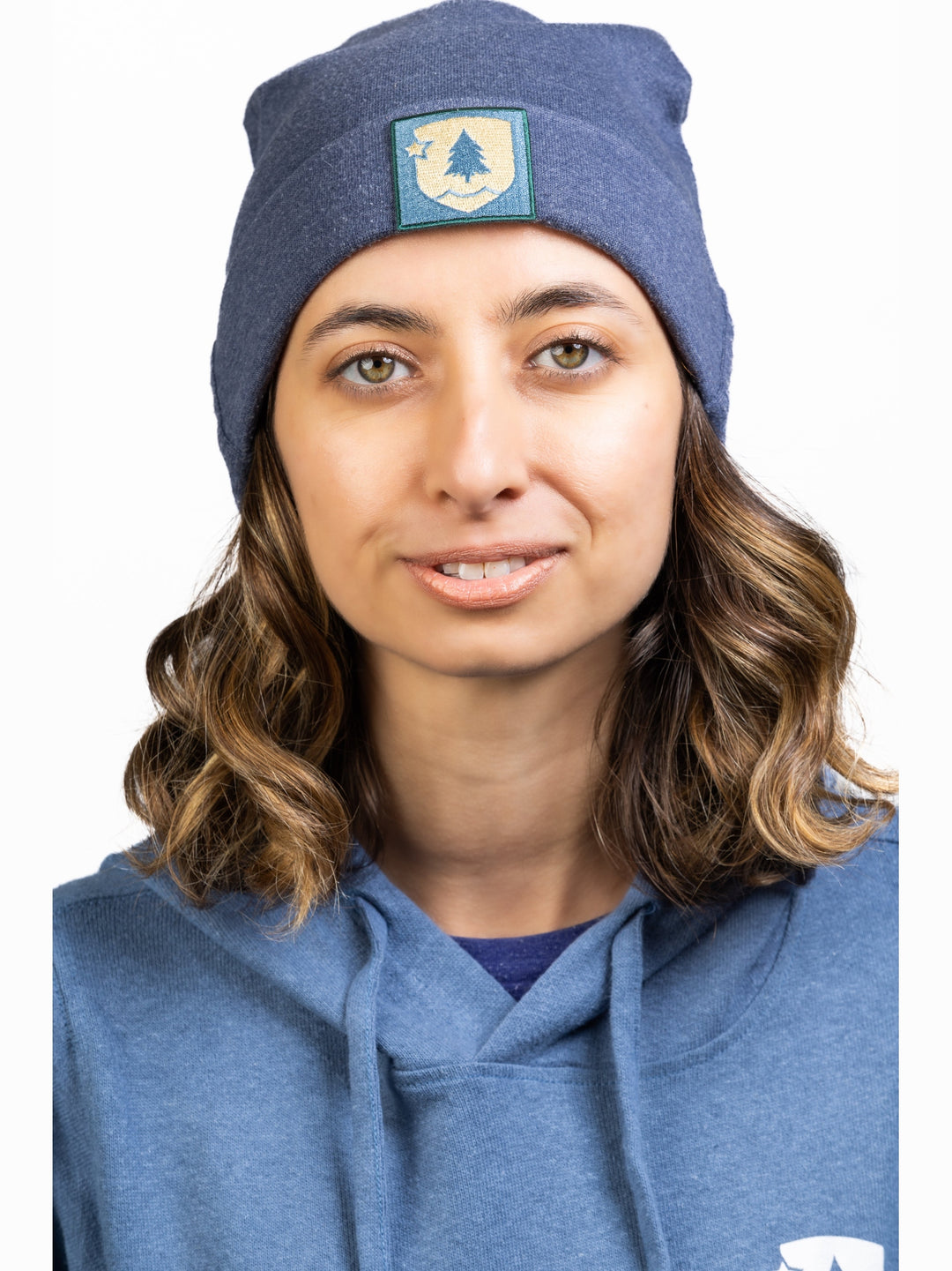 A person wearing a blue beanie with a patch on the front